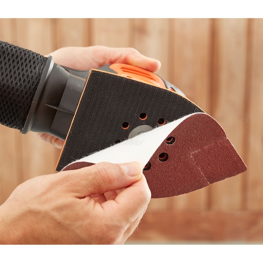 Foto van BLACKDECKER BEW200K detailschuurmachine met schuurvel dat wordt bevestigd, close-up.