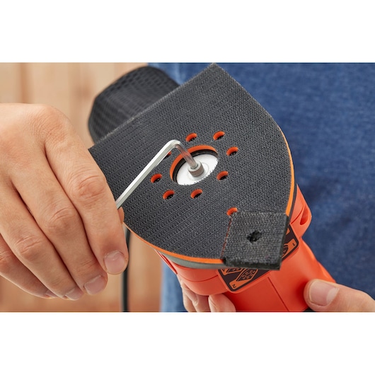 BLACKDECKER BEW200K schuurmachine close-up, pad wordt aangepast met inbussleutel, oranje en zwart.