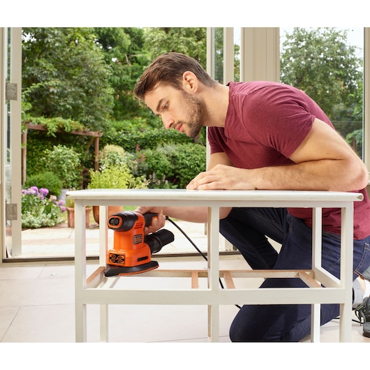 BLACKDECKER BEW200LSA schuurmachine gebruikt om wit houten tafelframe binnen nabij een raam glad te maken.