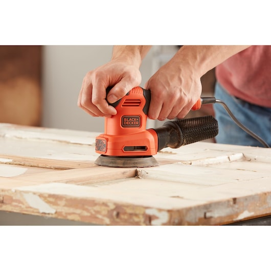 BLACKDECKER BEW200 oranje elektrische schuurmachine op een houten oppervlak, close-up.