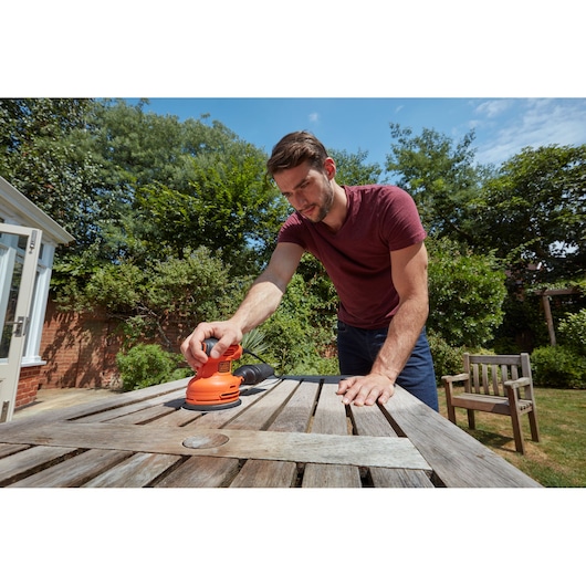 BLACK+DECKER BEW210 excenterschuurmachine gebruikt om een verweerde houten tuintafel te schuren.