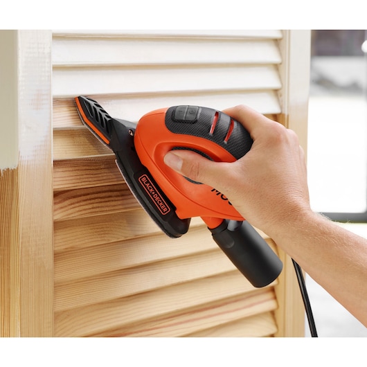 BLACKDECKER BEW230BCA ponceuse à main utilisée sur des stores en bois, photographie en gros plan.