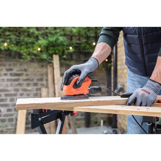 Fotografie van BLACKDECKER BEW230 muisschuurmachine in gebruik op houten plank buiten.