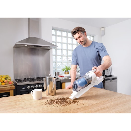 BLACKDECKER BHFEA420J aspirateur à main sans fil nettoyant du marc de café sur une table de cuisine.