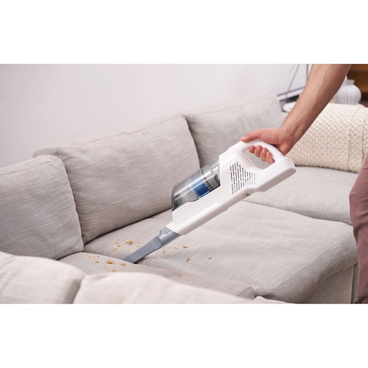 BLACKDECKER BHFEA420J aspirateur sans fil nettoyant des miettes sur un canapé gris, vue à main.