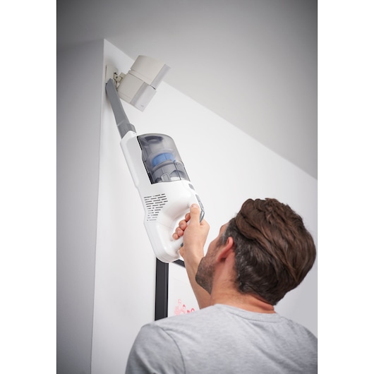 BLACKDECKER BHFEA420J aspirateur à main nettoyant un coin supérieur de mur, photographie en intérieur.