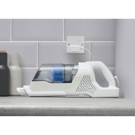 Aspirateur à main sans fil BLACKDECKER BHFEA420J blanc et bleu en charge sur un plan de travail, vue latérale.