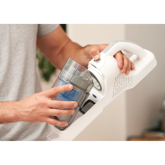 Photo du BLACKDECKER BHFEA420J aspirateur à main avec une personne retirant le récipient à poussière.
