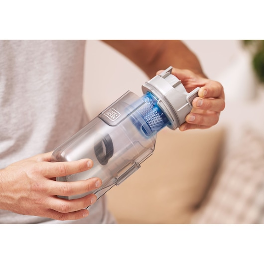 Photo du réservoir à poussière de l’aspirateur BLACK+DECKER BHFEA420J ouvert à la main, design en plastique argenté et bleu.