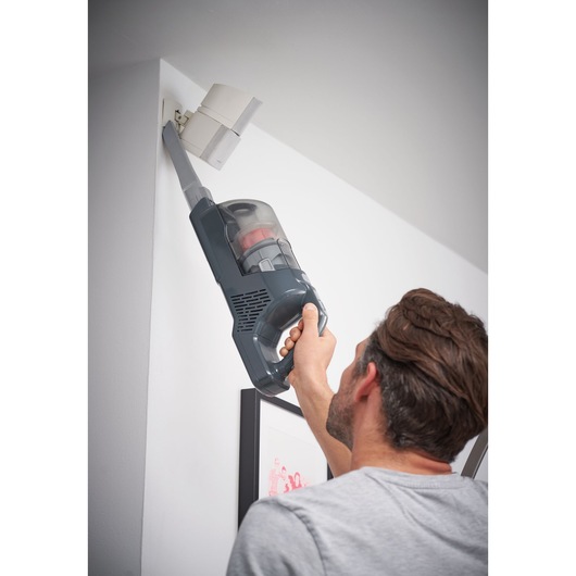 BLACKDECKER BHFEA520J aspirateur à main utilisé pour nettoyer un coin de plafond.