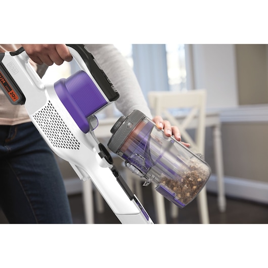 BLACKDECKER BHFEV1825CP draadloze stofzuiger in wit en paars, stofcontainer wordt binnenshuis geleegd.