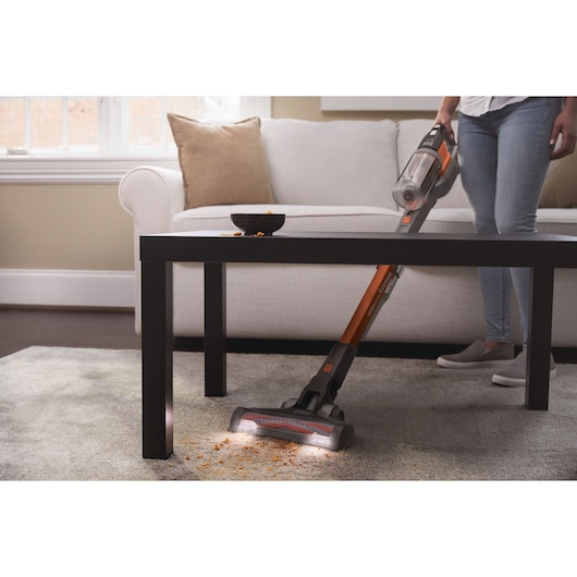 Aspirateur balai sans fil BLACKDECKER BHFEV182B nettoyant des miettes sur tapis dans un salon.