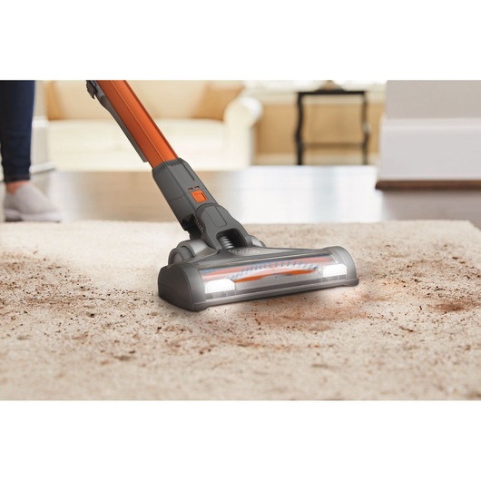 BLACKDECKER BHFEV182B tête d’aspirateur sans fil avec lumières LED nettoyant un tapis sale dans un salon.