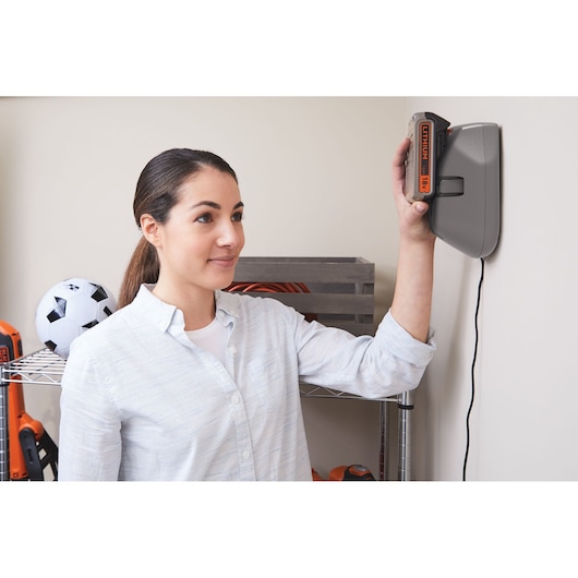 Photo de la batterie BLACKDECKER BHFEV182B en charge sur un chargeur mural dans une maison.
