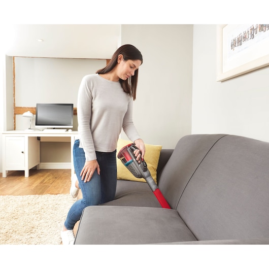 BLACKDECKER BHHV315J handstofzuiger reinigt grijze bank in woonkamer.