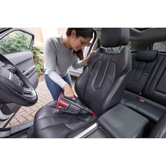 BLACKDECKER BHHV315J handstofzuiger reinigt zwarte autostoel in interieur.