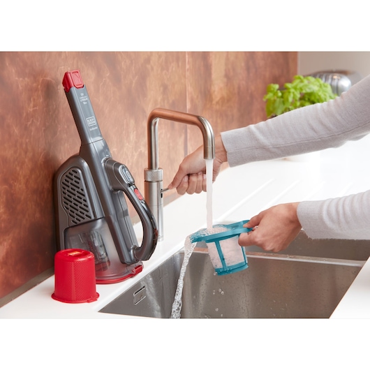 BLACKDECKER BHHV315J handstofzuigerfilter wordt onder keukenkran gewassen, stofzuiger op aanrecht.
