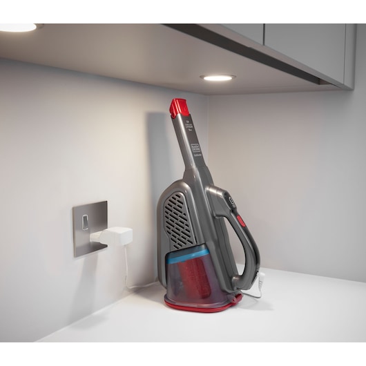 BLACKDECKER BHHV315J handstofzuiger grijs met rood aan het opladen op een aanrecht, zijaanzicht.