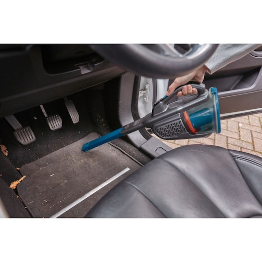 BLACK+DECKER BHHV320B handstofzuiger met verlengmondstuk reinigt automatten bij de pedalen.