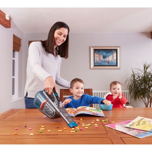BLACKDECKER BHHV320B handstofzuiger zuigt kruimels van houten tafel, kinderen zitten dichtbij.