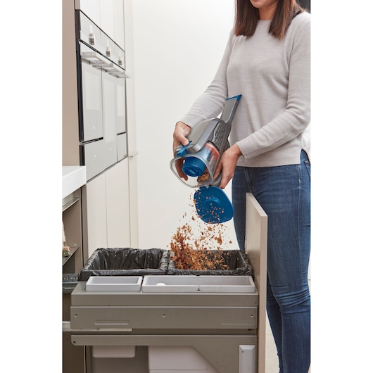 BLACKDECKER BHHV320J handstofzuiger wordt geleegd in een prullenbak in de keuken.