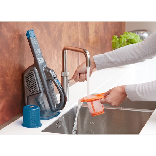 BLACKDECKER BHHV320J handstofzuigerfilter wordt onder een keukenkraan schoongemaakt, stofzuiger en onderdelen op het aanrecht.