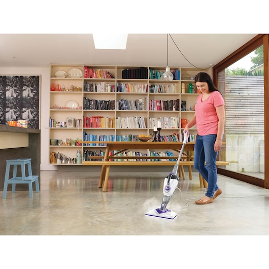 BLACK+DECKER BHSM1615DSM stoommop reinigt een lichte vloer in een moderne kamer met boekenplanken.