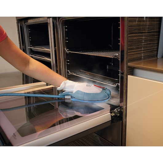 BLACKDECKER BHSM1615DSM stoomreinigingshandschoen reinigt een ovendeur, hand gebruikt het product.