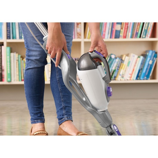 BLACK+DECKER BHSM1615DSM stoomreiniger met afneembare handunit in gebruik op vloer, boekenkast op de achtergrond.