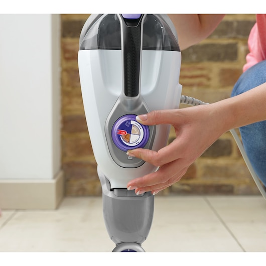 Close-upfoto van een hand die de draaiknop bedient op de BLACKDECKER stoomreiniger BHSM1615DSM.
