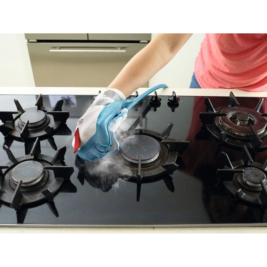 BLACKDECKER BHSM1615DSM stoomreinigingshandschoen gebruikt om een zwart gasfornuis schoon te maken, zichtbare stoom.