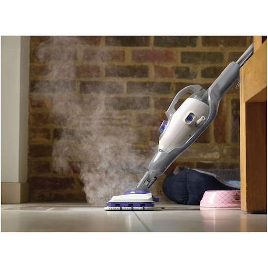 Foto van BLACKDECKER BHSM1615DSM stoommop die een tegelvloer reinigt, zichtbare stoom en ergonomisch grijs handvat.