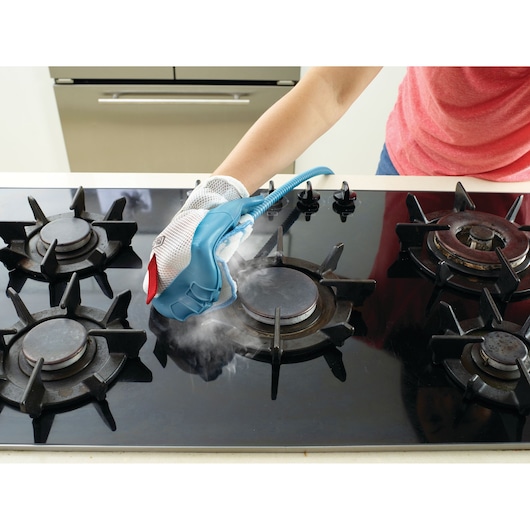 BLACKDECKER BHSM168DSM stoomreinigingshandschoen wordt gebruikt voor het schoonmaken van een zwart gasfornuis.