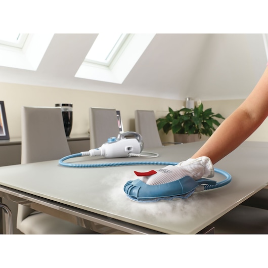 BLACKDECKER BHSM168DSM stoomreiniger gebruikt om een tafelblad schoon te maken, blauw-wit handapparaat met slang.