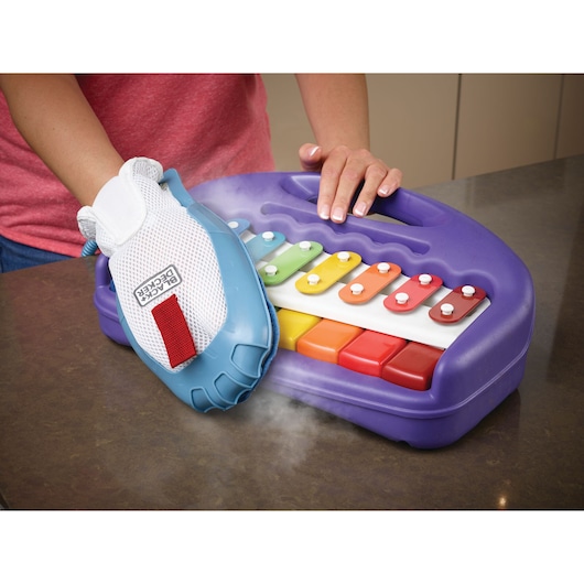 BLACKDECKER BHSM168DSM stoomreinigingshandschoen reinigt kleurrijk plastic xylofoon op aanrecht.