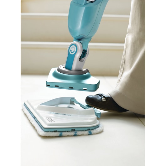BLACKDECKER BHSM168DSM stoommopkop wordt met de voet losgemaakt op witte tegelvloer, close-up.