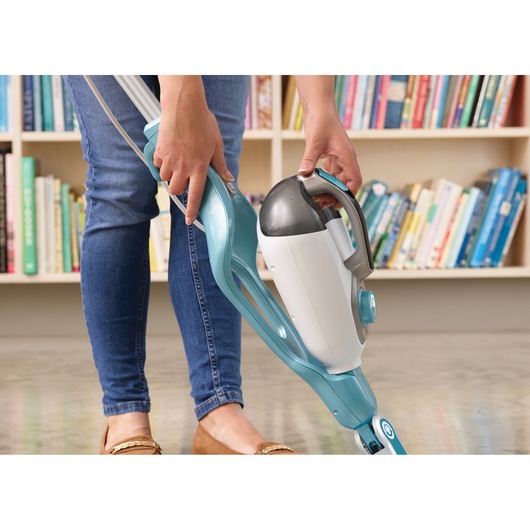 BLACKDECKER BHSM168DSM stoommop met afneembare handeenheid, blauw en wit, in gebruik op vloer bij boekenkast.