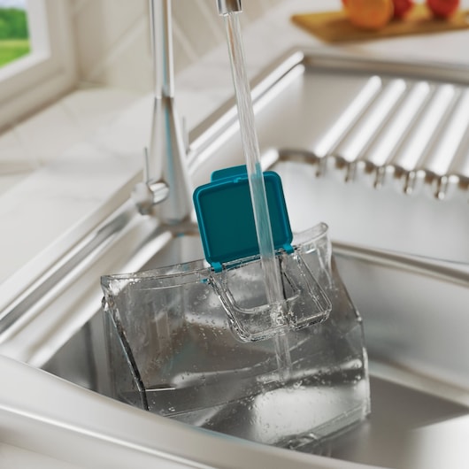 BLACK+DECKER BHSMP2314 transparante watertank met turquoise deksel onder keukenkraan, wordt gevuld met water, zijaanzicht.