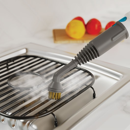BLACKDECKER BHSMP2314 handstoomreiniger borstel reinigt een fornuisrooster met zichtbare stoom.
