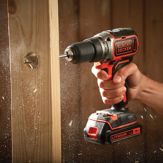 BLACK+DECKER BL186K perceuse sans fil en usage perçant du bois, gros plan avec copeaux visibles.