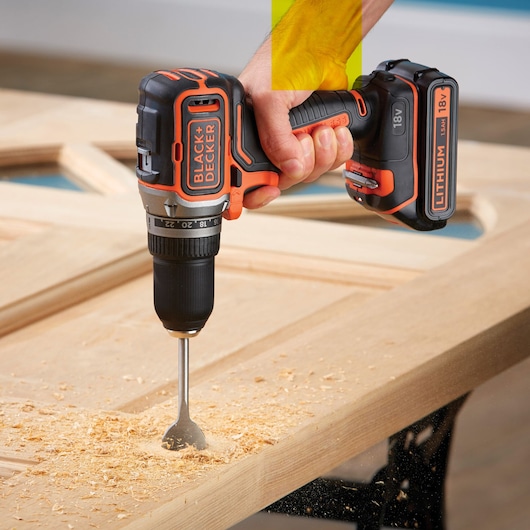 Photo de la perceuse sans fil BLACKDECKER BL186K avec batterie lithium 18V perçant une surface en bois.