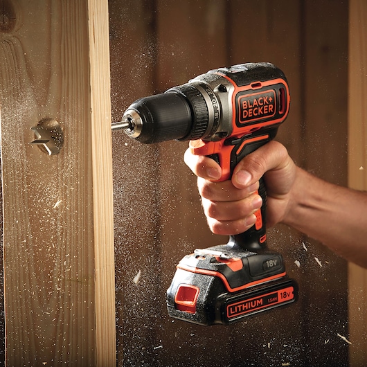 Perceuse sans fil BLACK+DECKER BL186N en utilisation, perçant du bois, batterie lithium 18V visible.