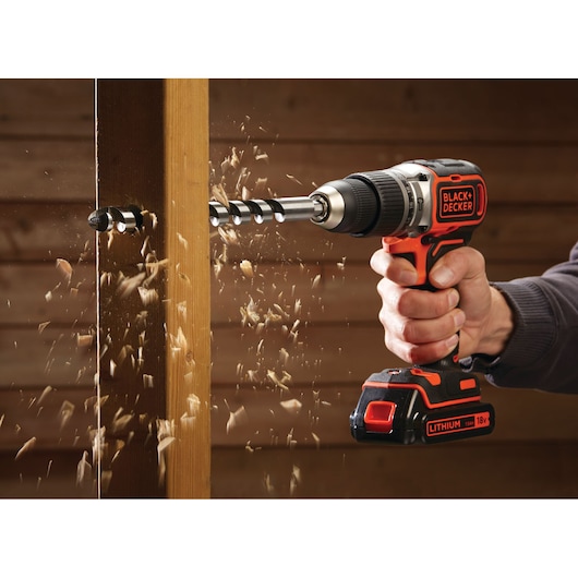 Photo de la perceuse sans fil BLACK+DECKER BL188N en action, perçant du bois avec des éclats.