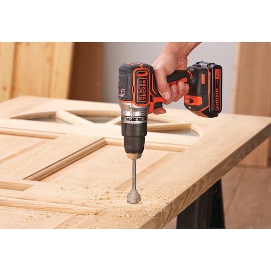 BLACKDECKER BL188N perceuse sans fil utilisée pour percer une porte en bois, photographie en gros plan.