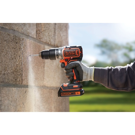 Photo de la perceuse sans fil BLACK+DECKER BL188N en cours d'utilisation, perçant un mur en béton à l'extérieur.