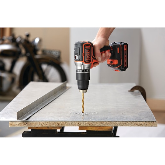 BLACK+DECKER BL188N perceuse sans fil utilisée pour percer une plaque métallique sur un établi.