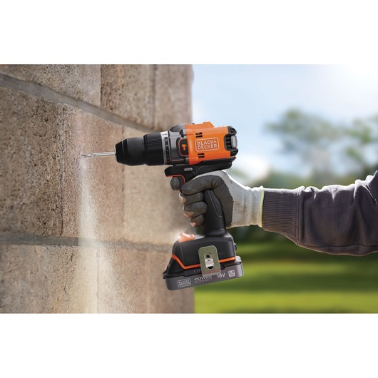 BLACKDECKER BLD683D1 perceuse sans fil orange et noire utilisée sur mur en pierre, extérieur.