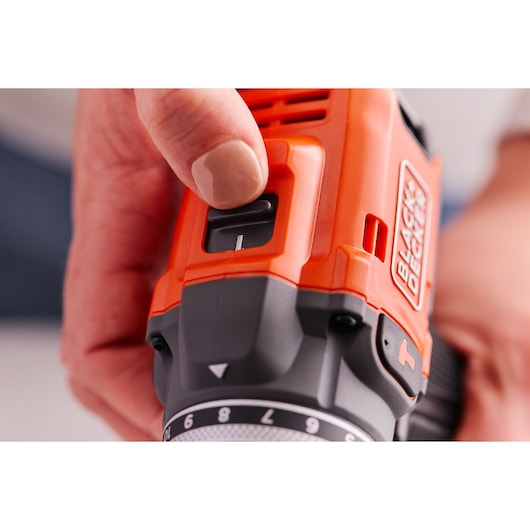 Photo en gros plan d'une main ajustant l’interrupteur de la perceuse sans fil orange et noire BLACK+DECKER BLD683D1.