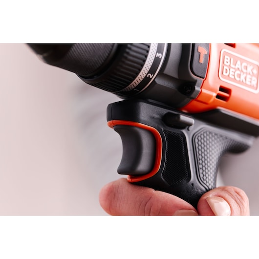 Vue rapprochée latérale de la poignée et de la gâchette de la perceuse BLACK+DECKER BLD683D1 tenue par une main, avec poignée texturée noire et orange.