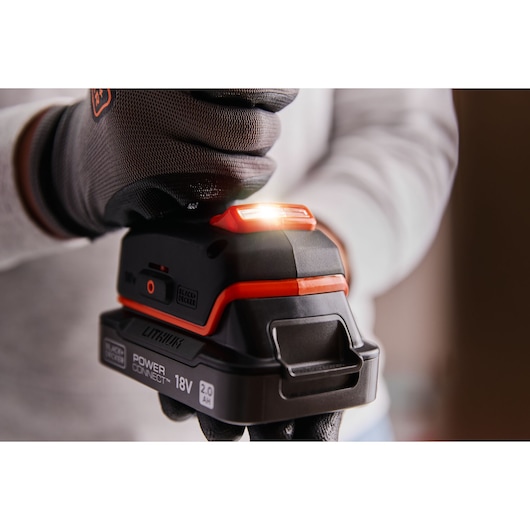 Photo en gros plan de la batterie d’outil BLACK+DECKER BLD683D1 18V lithium avec témoin lumineux, tenue par une main gantée.